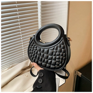 Detail of black semi-circular PU handbag with unique geometric embossed texture and gold buckle