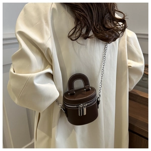 Dettaglio mini borsa a secchiello cilindrica marrone scuro con catena su cappotto