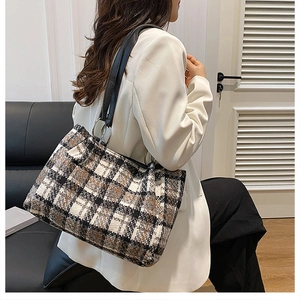 Detail of checkered tote bag with black leather straps and stylish metal ring buckle