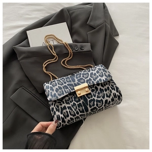 Close-up of leopard print shoulder bag with gold chain strap on grey blazer