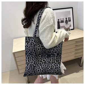 Detail view of large leopard print tote bag worn on shoulder over white knit sweater