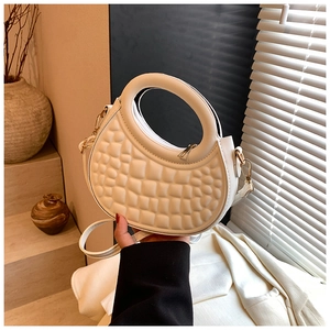 Close-up of white bubble texture PU leather handbag with gold hardware in soft home setting