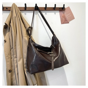 Detail of dark brown oil wax leather tote bag with decorative long straps and metal rings