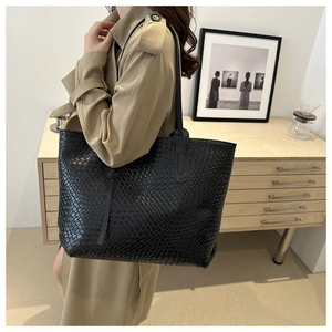 Close-up detail of the black woven leather texture on a large minimalist tote bag