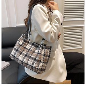 Close-up of black and white plaid tweed shoulder bag with leather strap and metal hardware