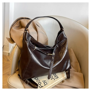 Detail of vintage brown leather tote bag with glossy finish and gold metal buckle hardware