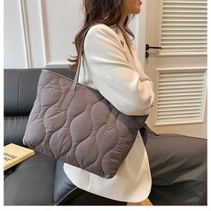 Primo piano di una grande borsa tote grigia trapuntata indossata da una modella