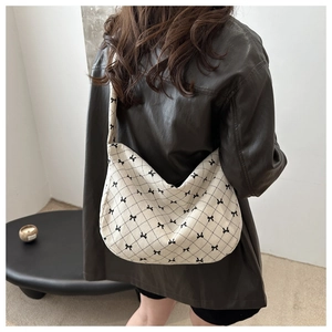 Dettaglio borsa tote in velluto a coste beige con fiocchi neri sulla spalla di una modella