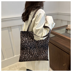 Detailed side view of the leopard print tote bag worn on shoulder in a warm indoor setting