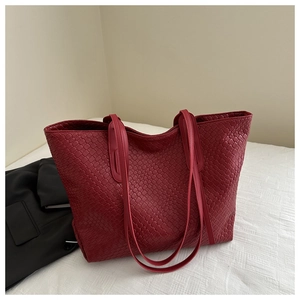 Detailed close-up of dark red tote bag featuring intricate woven texture on white bedding