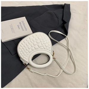 Detail of white PU leather crossbody bag featuring textured surface and gold hardware