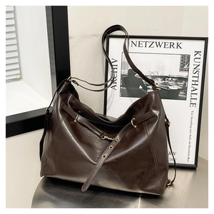 Detail of dark brown oily leather tote featuring polished gold hardware and vintage texture
