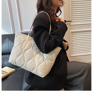 Dettaglio della borsa tote trapuntata beige con motivo a onde e tracolla in pelle