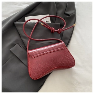 Detailed macro view of the burgundy crocodile pattern texture and metal buckle on the handbag