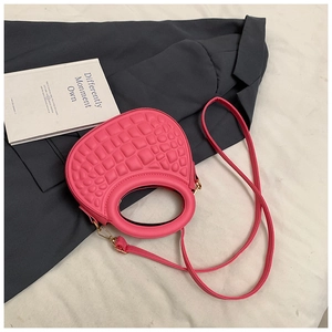 Detail of pink faux crocodile leather handbag with circular handle and gold hardware