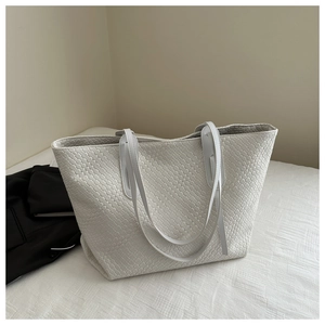 Close-up of cream woven tote bag showing detailed texture and dual shoulder straps