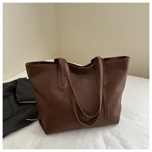 Detail shot of a dark brown woven tote bag with intricate leather weaving patterns