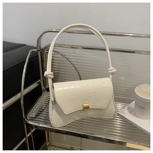 Detail of white crocodile pattern bag with golden square lock and knotted handle design