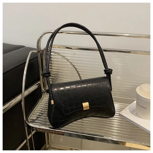 Detail of black crocodile texture shoulder bag with gold square buckle and knot strap