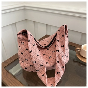 Borsa tote in velluto rosa con fiocchi neri e trama trapuntata su tavolo di legno