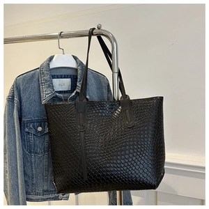 Detail of black woven texture on a large capacity tote bag hung on a metal rack