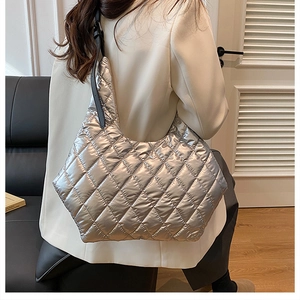 Silver quilted tote bag showing large capacity and metallic texture on model shoulder
