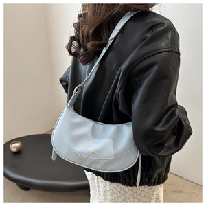 Detail of light blue lychee pattern leather shoulder bag with gold logo on a model