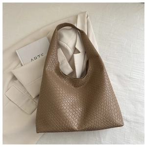 Détail de la texture tressée d'un grand sac hobo marron au style de bureau minimaliste