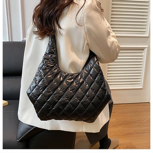 Close-up of black quilted hobo tote bag with diamond pattern stitching and glossy finish