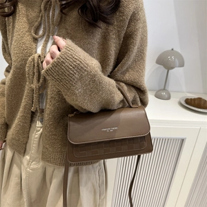 Chic brown leather crossbody bag with checkered pattern detail worn by a model