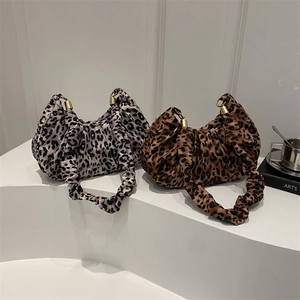 Sac à main vintage à motif léopard avec détails dorés sur un socle blanc épuré