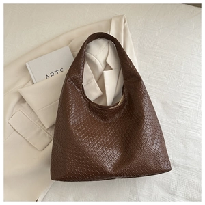 Gros plan sur la texture tressée et la finition en similicuir de ce sac cabas marron café