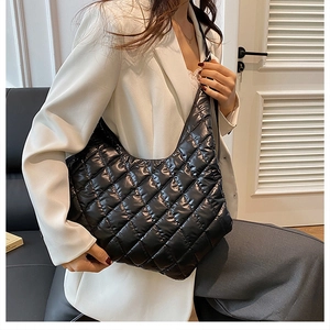 Close-up of black quilted puffer tote bag featuring classic diamond stitched pattern and soft texture
