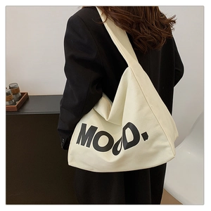 Close-up of beige canvas tote bag featuring MOOD letter print with wide shoulder strap