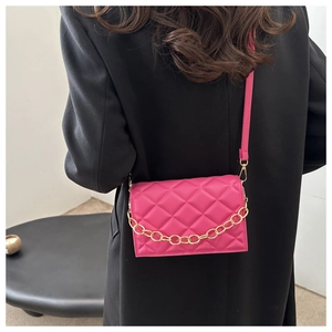 Close-up of fuchsia quilted crossbody bag with gold chain on black coat fashion view