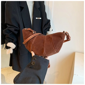 Dettaglio borsa a mezzaluna in camoscio marrone scuro con cuciture curve e zip