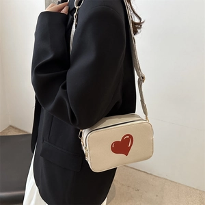 Minimalist beige camera bag with red heart print and wide adjustable strap