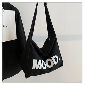 Close-up of black canvas tote bag with white MOOD lettering and durable zipper closure