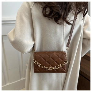 Close-up of brown quilted leather crossbody bag with decorative gold metal chain strap
