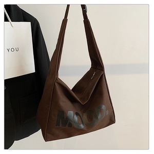 Brown canvas hobo tote bag with MOOD lettering and zipper closure shown in stylish setting