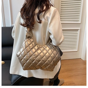 Detailed back view of a metallic bronze quilted tote bag on a model in a white blazer