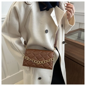 Close-up of brown quilted bag with gold chain strap and elegant brand lettering