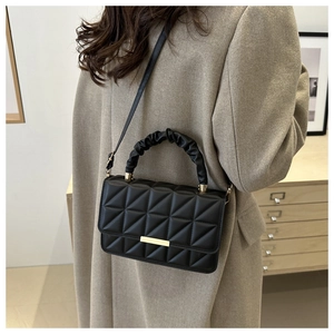 Detail of black quilted shoulder bag featuring gold-tone metal trim and gathered handle
