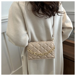 Close-up of cream quilted crossbody bag with gold chain and adjustable leather strap