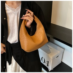 Detail of a brown woven crescent tote bag showing the intricate faux leather texture
