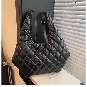 Detail of black quilted puffer tote bag with silver buckle and nylon texture