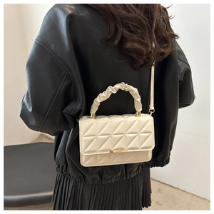 Detail of cream quilted crossbody bag with cloud pleat handle and gold chain hardware