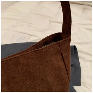 Detailed view of the dark brown suede fabric texture and wide shoulder strap seam