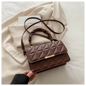 Close-up of diamond-quilted leather texture with gold metal buckle and pleated handle
