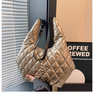 Detail of metallic gold quilted tote bag with black adjustable strap and stitching
